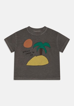Camiseta de algodón gris con mangas cortas, con un gráfico colorido de una palmera, el sol y una colina amarilla, con el texto "SUEÑA BAJO EL SOL."