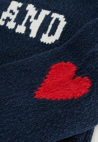 Granatowa dzianina z białymi napisami i czerwonym motywem serca. Tekstura jest miękka, o grubym, tkanym wyglądzie.