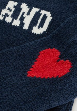 Gestrickter marineblauer Stoff mit weißen Buchstaben und einem roten Herzmotiv. Die Textur ist weich mit einem groben, gewebten Erscheinungsbild.