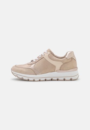 Beige og lysebrun sneaker med snørelukning foran, polstret krave og tyk hvid sål med mønster, vist fra venstre side på ensfarvet baggrund.