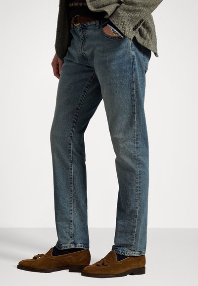 Light blue, straight-fit jeans with slight fading, crafted from denim. Paired with brown suede loafers featuring a tassel detail.