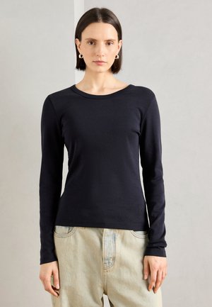 Langermet marineblå topp laget av myk stoff, med rund hals og en slim fit. Synlig merkevarelogo nederst.