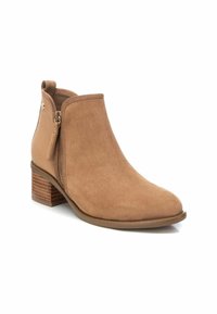 Stivaletto alla caviglia in suede tan con zip laterale, punta rotonda e tacco in legno impilato. Presenta una texture liscia e pochi dettagli in metallo.