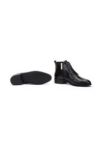 Botas de cuero negras hasta el tobillo con cordones en la parte delantera y cremallera lateral, que cuentan con una suela texturizada y un detallado decorativo de broguing.