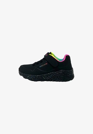 Zwarte sneaker met een textuur oppervlak, voorzien van een klittenbandsluiting en meerkleurige accenten. De zool heeft een gespikkeld patroon voor extra detail.