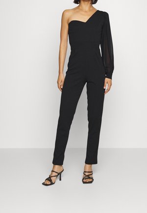 Zwarte one-shoulder jumpsuit met een getailleerde bodice en lange, gekruiste mouw. Gemaakt van gladde stof, met een taps toelopend broekontwerp en minimale accenten.