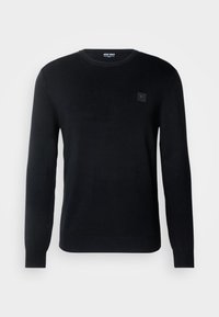 Pull noir à col rond avec manches longues et petit écusson logo carré sur la poitrine gauche, présenté sur un fond uni.