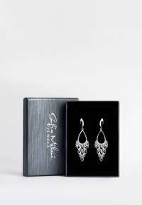 Orecchini a goccia d'argento con dettagli floreali, appesi a un cerchio. Presentati in una scatola regalo rivestita di velluto nero con un'esterno argentato metallico.