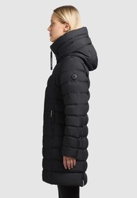 Black puffer coat with a high collar and hood, featuring a quilted design, side zipper pockets, and logo hardware on the left sleeve.