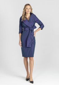 Granatowa sukienka typu wrap z wiązaniem w talii, rękawami trzyczwartowymi i długością do kolan, uszyta z gładkiego, błyszczącego materiału.