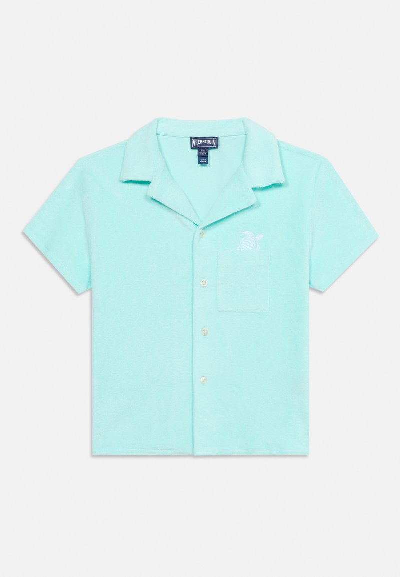 Ανοιχτό μπλε πουκάμισο με κοντά μανίκια, κουμπιά, λαιμόκοψη, τσέπη στο στήθος και μικρό κεντημένο σχέδιο χελώνας πάνω από την τσέπη.