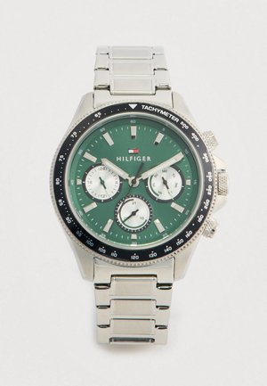 Tommy Hilfiger stainless steel watch with green dial, three white subdials, tachymeter bezel, and date, day, and 24-hour indicators.