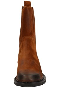 Bottine en daim marron avec une semelle noire lisse, des panneaux latéraux élastiques et un embout légèrement arrondi. Présente des coutures nettes le long des coutures.