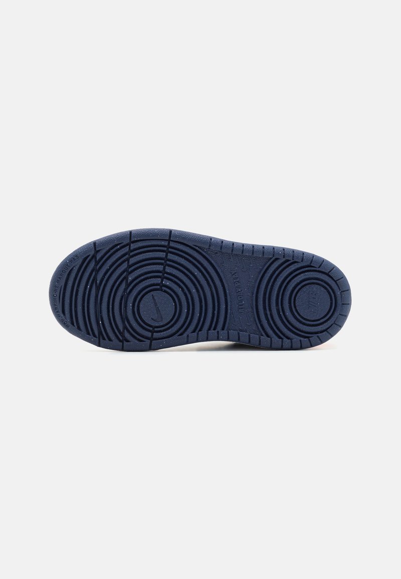 Blauer Gummisohle eines Sneakers mit zirkularen Profilmustern, strukturierten Oberflächen und sichtbar vorhandenem Markenlogo. Sauberes, minimalistisches Design.
