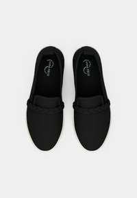 Black slip-on shoes made of soft fabric, featuring a braided accent over a padded tongue and a white rubber sole. Smooth texture, casual design.