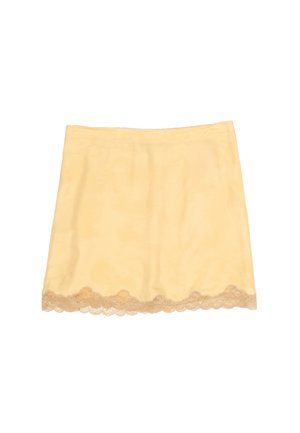 Falda tipo slip amarilla clara con borde de encaje festoneado en el dobladillo, sobre un fondo blanco liso.