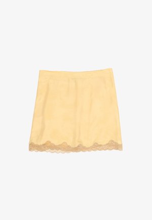 Falda tipo slip amarilla clara con borde de encaje festoneado en el dobladillo, sobre un fondo blanco liso.