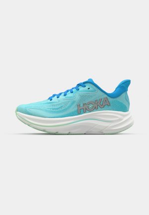 Hellblaues Sport Schuhwerk mit einem Netz-Obermaterial, kontrastierenden blauen Schnürsenkeln und einer dicken weißen Sohle. Verfügt über ein erhabenes Markenlogo an der Seite.