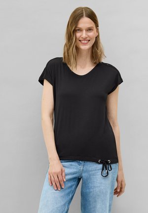 Schwarzes kurzärmeliges T-Shirt mit Rundhalsausschnitt, ausgestattet mit einem Kordelzugsaum und leichtem Stoff, kombiniert mit hellblauen Jeans.