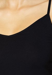 Czarny dopasowany tank top z cienkimi ramiączkami i dekoltem w serek, wykonany z gładkiego, elastycznego materiału. Brak widocznych wzorów lub akcentów.