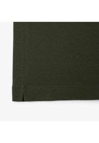 Mörkgrön texturerad tyg med en slät yta. Nederkanten har en liten spricka som ger en subtil detalj till designen.