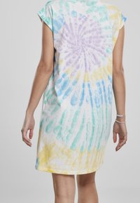 Bawełniana sukienka tie-dye w kolorze białym, z spiralnym wzorem w pastelowym niebieskim, żółtym i purpurowym. Krótkie rękawy i luźny krój.