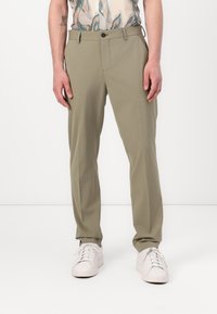 Khaki bukser med lige ben-design, lavet af glat stof, med knaplukning og sidelommer, parret med hvide sneakers.