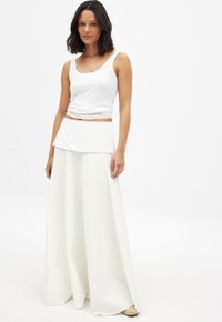 White tank top paired with a flowy white maxi skirt. The skirt features a layered, folded waistband and a soft, smooth texture.