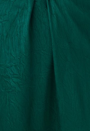 Tmavě zelená látka s viditelnými vráskami a měkkými záhyby vytvářející texturu a hloubku.