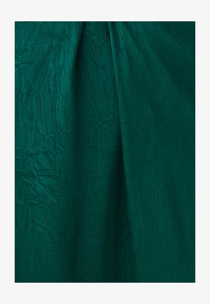 Tmavě zelená látka s viditelnými vráskami a měkkými záhyby vytvářející texturu a hloubku.