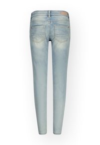 Vaqueros ajustados de mezclilla de color azul claro. Cuentan con una cintura de altura media, dos bolsillos traseros, detalles descoloridos y una etiqueta con el logo en la cinturilla.