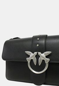 Borsa a tracolla nera in pelle con chiusura a patta, dotata di decorazione a forma di uccello in tonalità argento e dettagli con borchie sulla tracolla frontale.