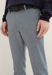 Sivé štruktúrované nohavice so slim fit strihom, s čiernym opaskom. Detailný záber zdôrazňujúci látku a švy.