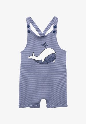 Une combinaison pour bébé rayée bleue et blanche avec des bretelles réglables à boutons et un graphique d'une baleine souriante crachant de l'eau sur le devant.