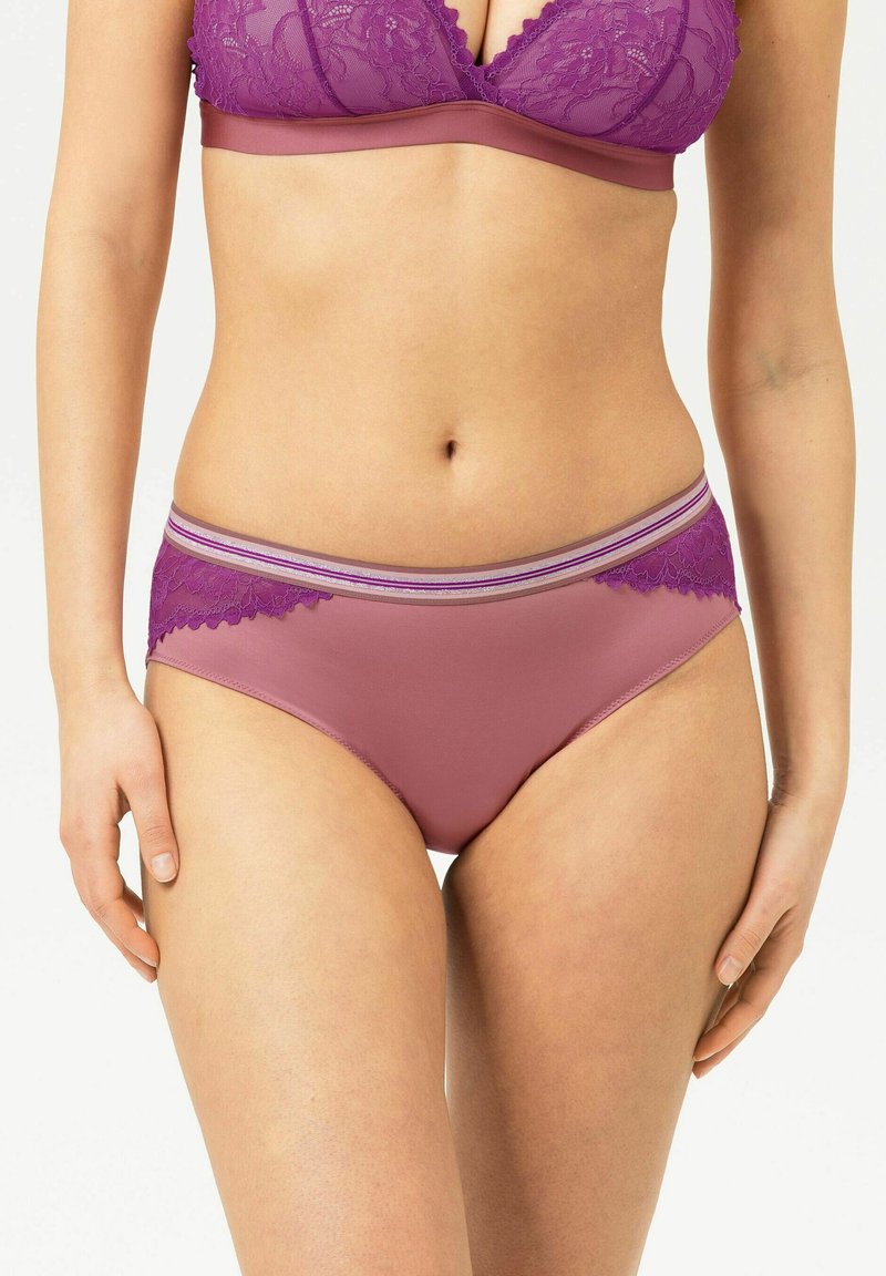 Woman wearing matching purple lace bra and panties, shown from mid-torso to upper thighs against white background.