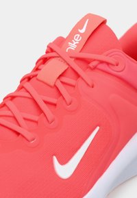Αθλητικό παπούτσι Nike για τρέξιμο σε έντονο κοραλί χρώμα με λείο υφασμάτινο επάνω μέρος, αντίθετο λευκό λογότυπο swoosh και υφασμένο λαστιχένιο πέλμα.