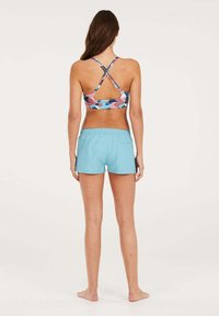 Sportinė liemenėlė su daugiaspalviu geometrijos raštu mėlynos, rožinės ir violetinės spalvų, derinama su šviesiai mėlynomis šortais, kurie turi raištelį ir šonines kišenes.