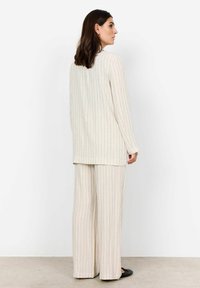 Cremefarbenes, gestreiftes Loungewear-Set mit langärmeligem Oberteil und weit geschnittenen Hosen, das vertikale Linien in dezenten Blau- und Beigetönen aufweist.