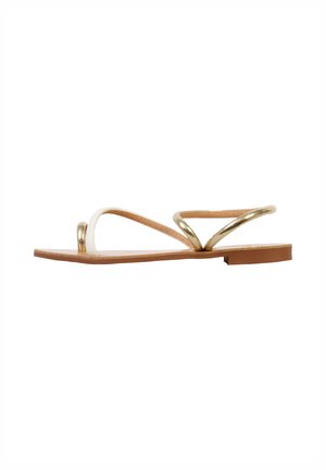 Flat sandal with tan sole, white toe strap, and metallic gold ankle strap against a white background.