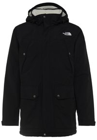 Parka isolante noire avec capuche, deux poches poitrine, deux poches basses à rabat et doublure en polaire blanche visible à l'intérieur de la capuche.