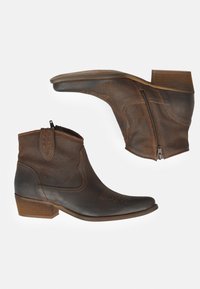 Las botas de tobillo de cuero marrón cuentan con una punta afilada, cremallera lateral y costuras decorativas. El tacón es de estilo bloque, lo que aporta estabilidad.
