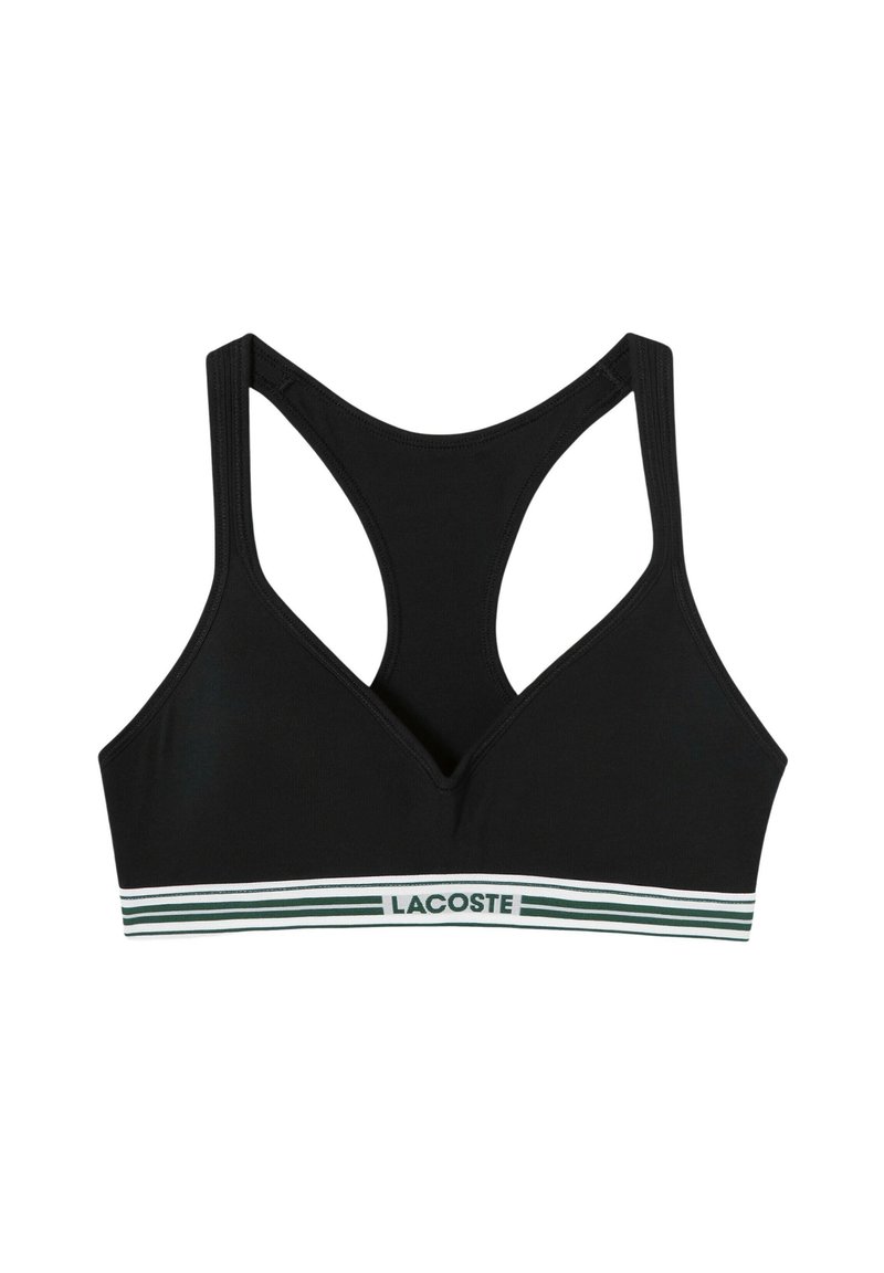 Sujetador deportivo negro con escote en forma de V y tirantes anchos estilo racerback. Presenta una banda a rayas verde y blanca con el logotipo de "LACOSTE". Textura suave.