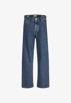 T-shirt bianco a maniche corte abbinato a jeans in denim blu larghi e sneaker bianche, su uno sfondo chiaro e uniforme.