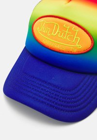 Kapa s duginim gradientom i plavim vizorom, sa istaknutom narančastom oznakom. Izrađena je od tkanine s vidljivim detaljima šivanja.