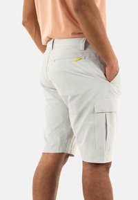 Bermuda cargo grigie chiare realizzate in tessuto morbido; presenta due tasche laterali e una tasca posteriore con zip e un gancetto giallo.