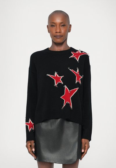 Black sweater with red star motifs and frayed accents, paired with a black leather skirt. Soft knit fabric, relaxed fit, crew neckline.