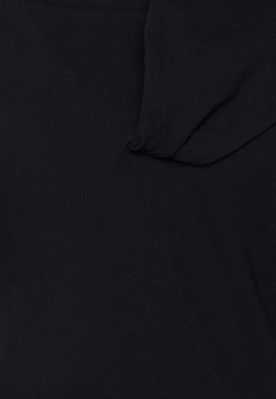 O tecido de algodão preto apresenta uma textura suave com ligeira elasticidade. Um detalhe suave e dobrado é visível, adicionando uma dimensão subtil.