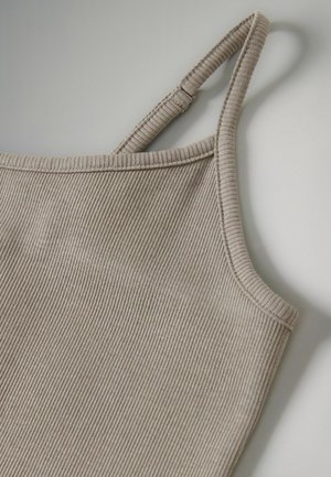 Beige tanktop met ribbelpatroon, smalle bandjes en een aansluitend design. Close-up toont fijne textuur en nette stiksels langs de halslijn en bandjes.