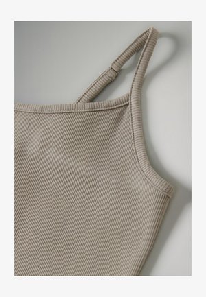 Beige tanktop met ribbelpatroon, smalle bandjes en een aansluitend design. Close-up toont fijne textuur en nette stiksels langs de halslijn en bandjes.