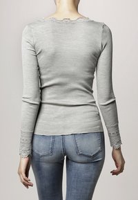 Grå ribbad långärmad topp med en scallop-formad halsringning och spetsdetaljer vid ärmsluten, figurnära design och rak nertill.